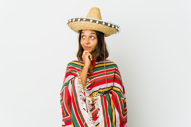 Young mexican woman isolated on white relaxed thinking about something looking at a copy space.