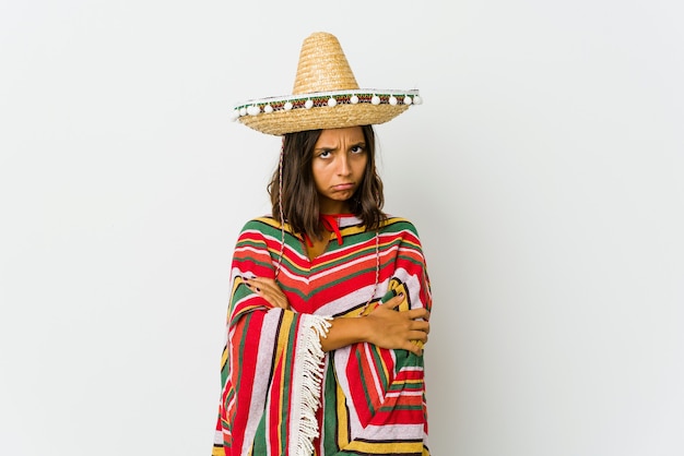 Young mexican woman isolated on white wall frowning face in displeasure, keeps arms folded.