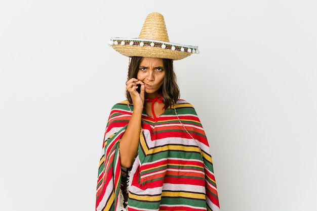 Young mexican woman isolated on white with fingers on lips keeping a secret.