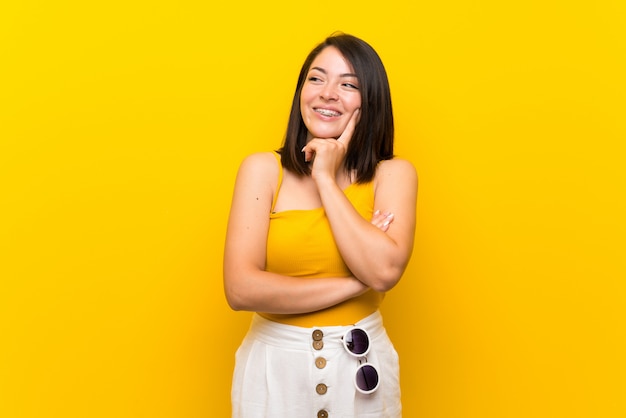 Young mexican woman over isolated yellow looking to the side