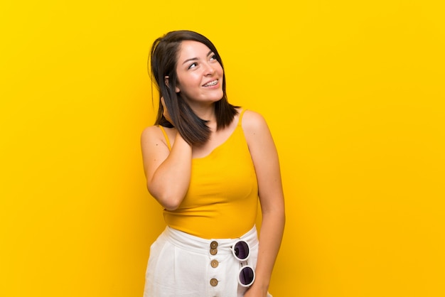 Young Mexican woman over isolated yellow thinking an idea