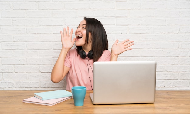 Young Mexican woman with a laptop shouting with mouth wide open