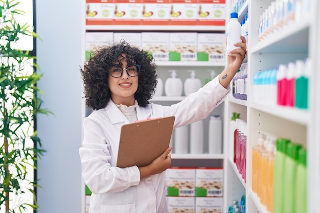 Young middle eastern woman pharmacist reading document at pharmacy