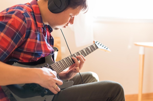 Young millennial man, guy playing electric guitar. Stay at home, home activity, learning classes