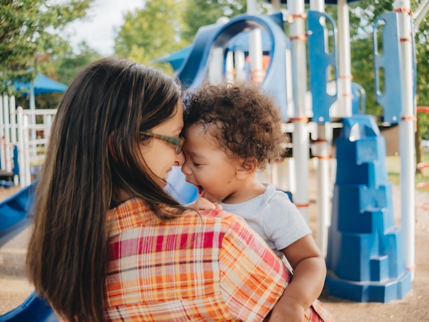 Photo young millennial mother and diverse toddler boy bonding together outdoors at local park