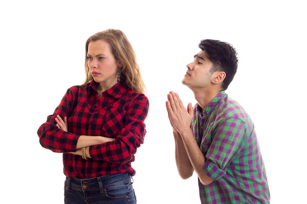 Young mirthless woman with young handsome man with dark hair in plaid shirts arguing