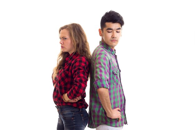 Young mirthless woman with young handsome man with dark hair in plaid shirts quarreling