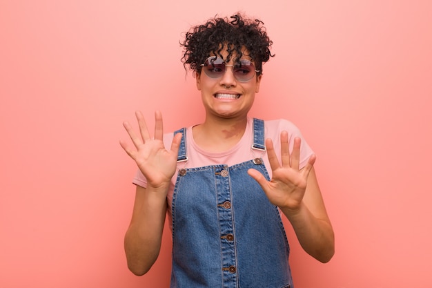 Young mixed african american teenager woman rejecting someone showing a gesture of disgust.