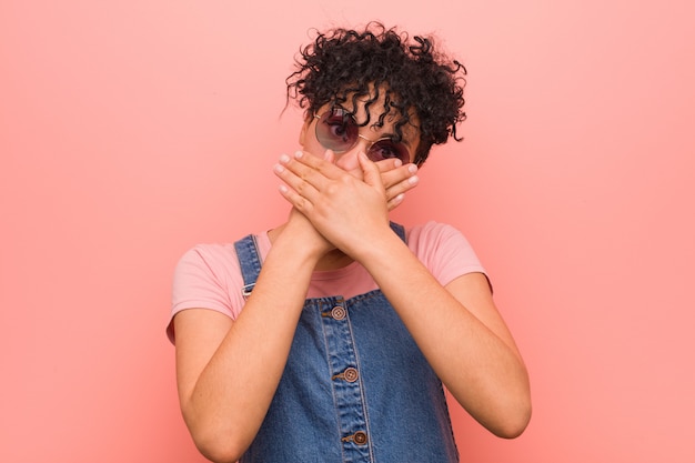 Young mixed african american teenager woman shocked covering mouth with hands.