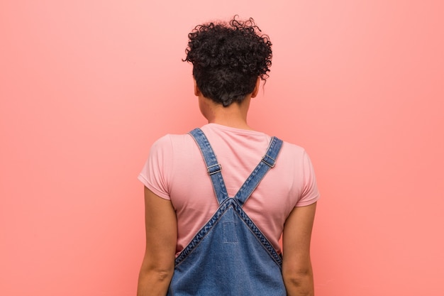 Young mixed african american teenager woman showing strength gesture with arms, symbol of feminine power