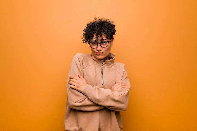 Young mixed african american woman against a brown wall unhappy looking in camera with sarcastic expression.