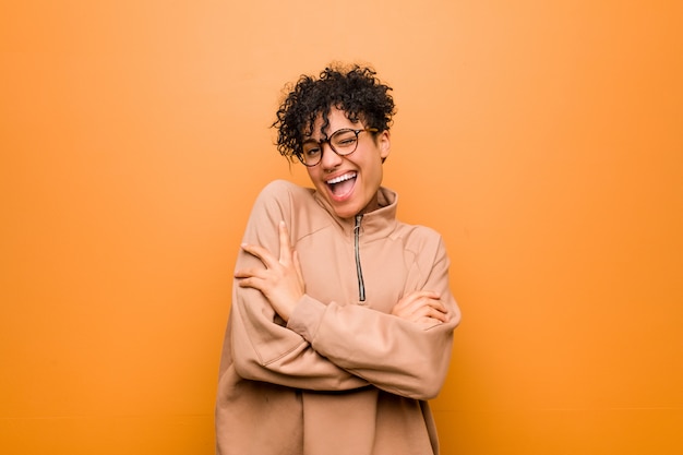 Young mixed african american woman against a brown wall who feels confident, crossing arms with determination.