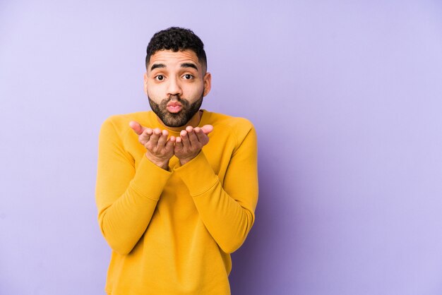 Young mixed race arabic man isolated folding lips and holding palms to send air kiss.