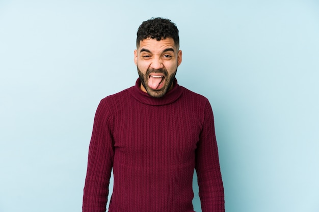 Young mixed race arabic man isolated funny and friendly sticking out tongue.