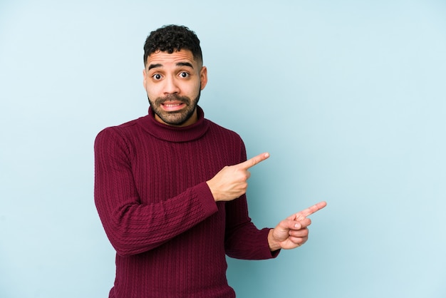 Young mixed race arabic man isolated shocked pointing with index fingers to a copy space.