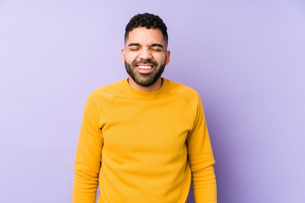 Young mixed race arabic man laughs and closes eyes, feels relaxed and happy.