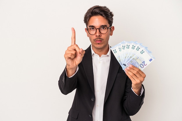 Young mixed race business man holding bills isolated on white background showing number one with finger.