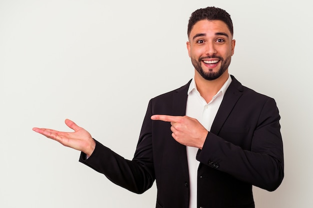 Young mixed race business man isolated on white wall excited holding a copy space on palm.