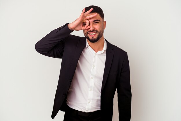 Young mixed race business man isolated on white wall excited keeping ok gesture on eye.