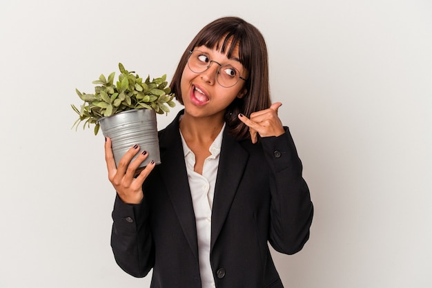 Young mixed race business woman holding a plant isolated on white background showing a mobile phone call gesture with fingers.