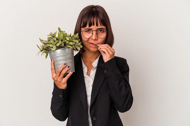 秘密を保持している唇に指で白い背景で隔離の植物を保持している若い混血ビジネス女性。