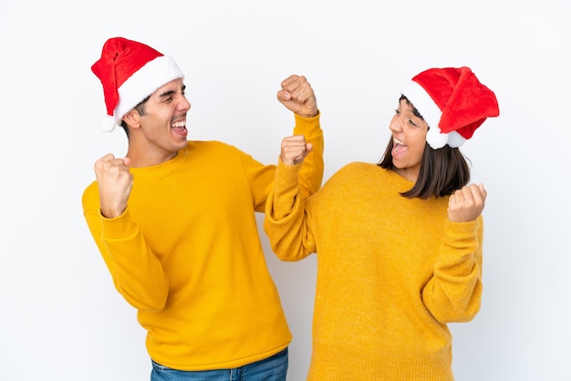 Young mixed race couple celebrating Christmas isolated on white background celebrating a victory in winner position