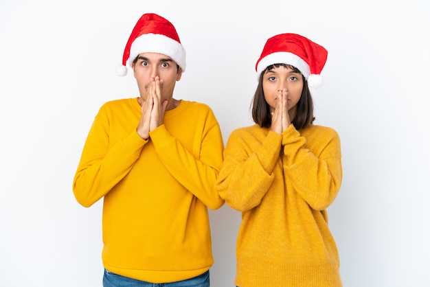 Young mixed race couple celebrating Christmas isolated on white background keeps palm together. Person asks for something