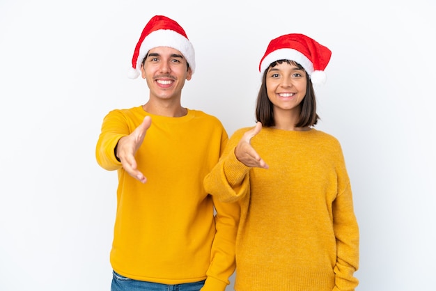 Молодая пара смешанной расы празднует Рождество на белом фоне, пожимая руку для заключения хорошей сделки