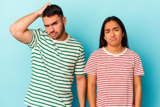 Young mixed race couple isolated on blue being shocked, she has remembered important meeting.