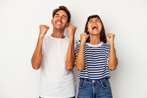 Young mixed race couple isolated on white background celebrating a victory, passion and enthusiasm, happy expression.