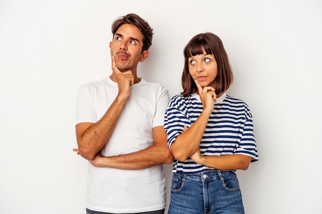 Young mixed race couple isolated on white background contemplating, planning a strategy, thinking about the way of a business.