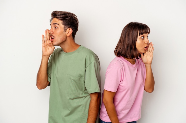 Photo young mixed race couple isolated on white background is saying a secret hot braking news and looking aside