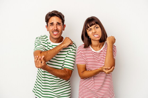 Young mixed race couple isolated on white background massaging\
elbow, suffering after a bad movement.