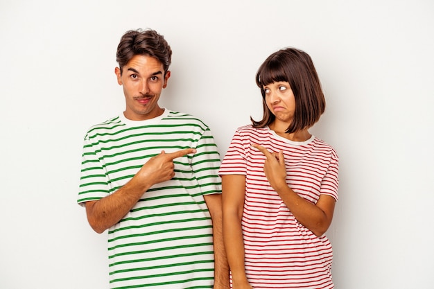 Young mixed race couple isolated on white background smiling and pointing aside, showing something at blank space.