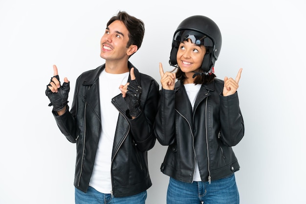 Young mixed race couple with a motorcycle helmet isolated on white background pointing with the index finger a great idea