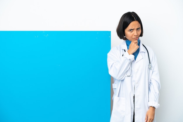 Young mixed race doctor woman with a big placard isolated on white background having doubts