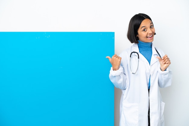 製品を提示する側を指している白い背景に分離された大きなプラカードを持つ若い混血医師の女性
