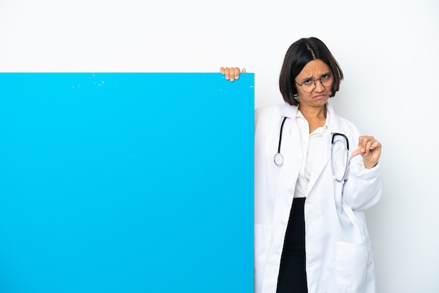 Молодая женщина-врач смешанной расы с большим плакатом, изолированным на белом фоне, показывает палец вниз двумя руками