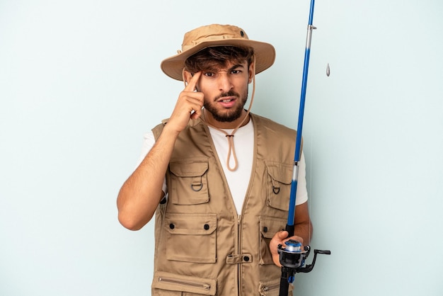 Young mixed race fisherman holding a rod isolated on blue background showing a disappointment gesture with forefinger.