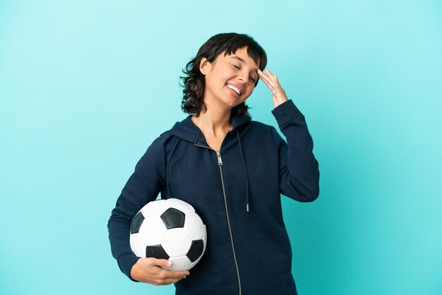 Young mixed race football player woman isolated on blue\
background smiling a lot