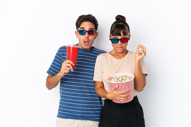 Young mixed race friends isolated on white background with 3d glasses and holding a big bucket of popcorns