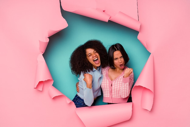 Young mixed race friends in torn paper isolated on blue background