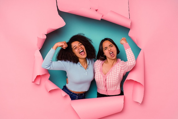 Young mixed race friends in torn paper isolated on blue background