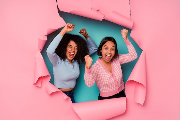 Young mixed race friends in torn paper isolated on blue wall