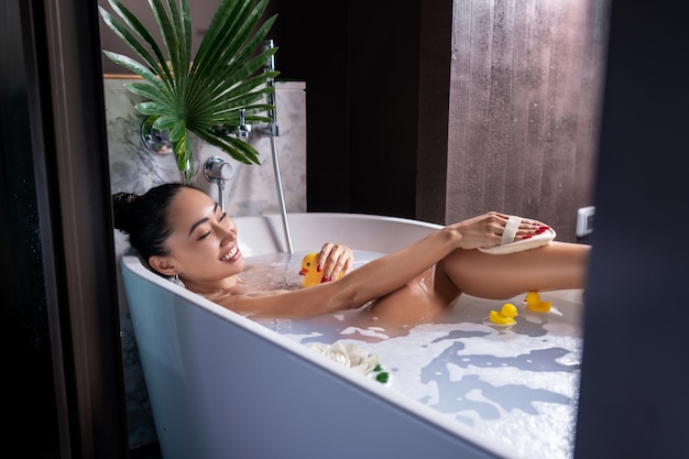 A young mixed-race girl posing while lying in a foam bath near the open top