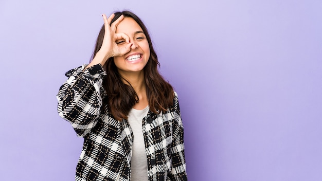 Young mixed race hispanic woman isolated excited keeping ok gesture on eye.