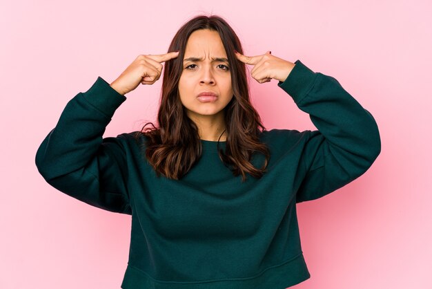 Foto la giovane donna ispanica di razza mista isolata si è concentrata su un compito, mantenendo gli indici che puntano la testa.