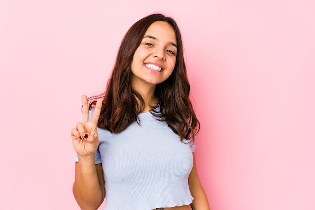 Young mixed race hispanic woman isolated joyful and carefree showing a peace symbol with fingers.