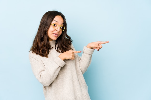 Young mixed race hispanic woman isolated pointing with forefingers to a copy space, expressing excitement and desire.