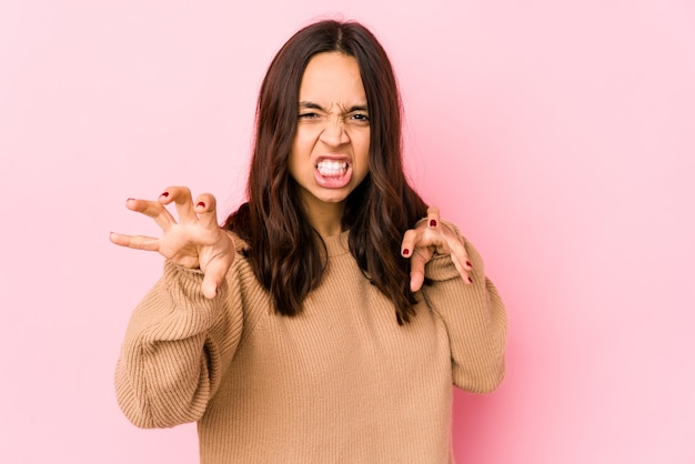 Young mixed race hispanic woman isolated showing claws imitating a cat, aggressive gesture.